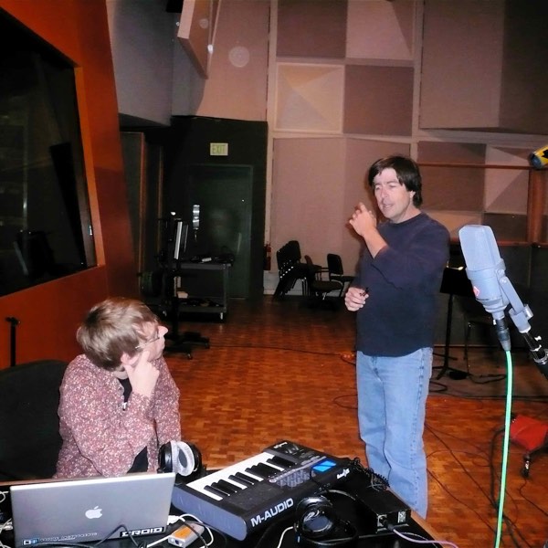 Thomas Newman standing in a scoring stage talking to John von Seggern, who is seated at a laptop and MIDI keyboard