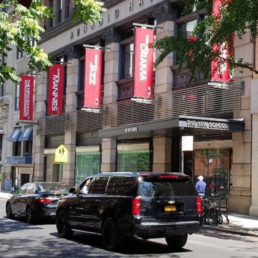 The New School's Arnold Hall seen from across the street, red banners for Mannes, Jazz and Drama hanging from its facade